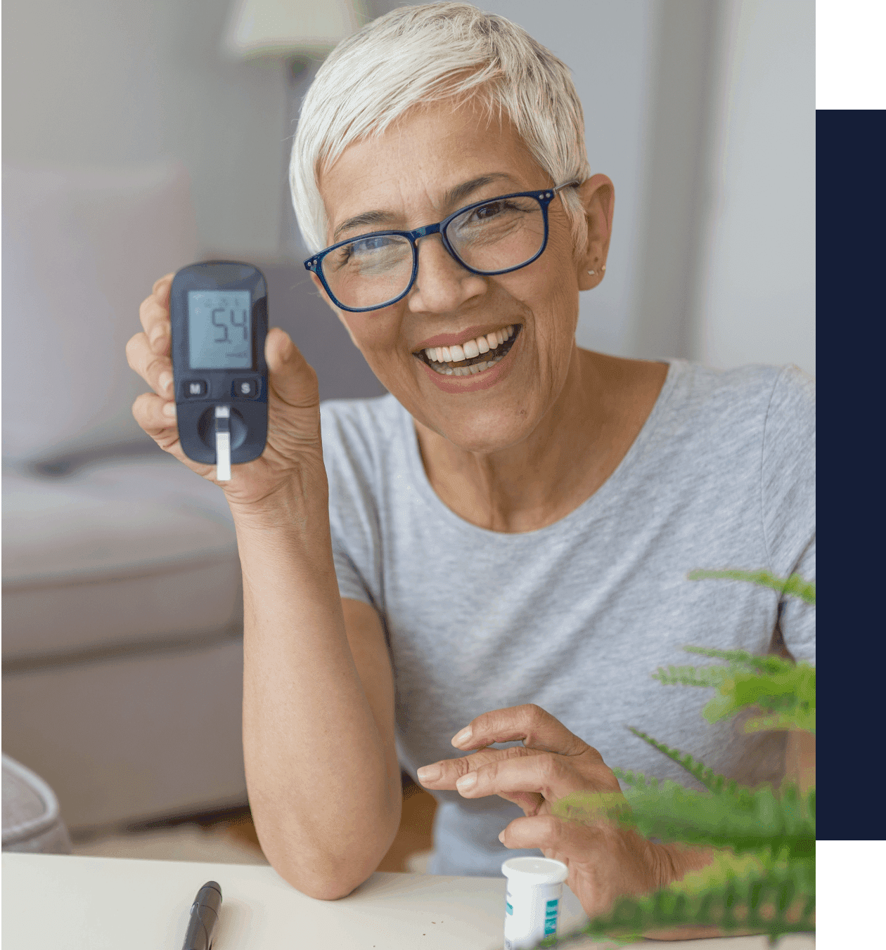 A woman holding up a glucose meter in her hand.